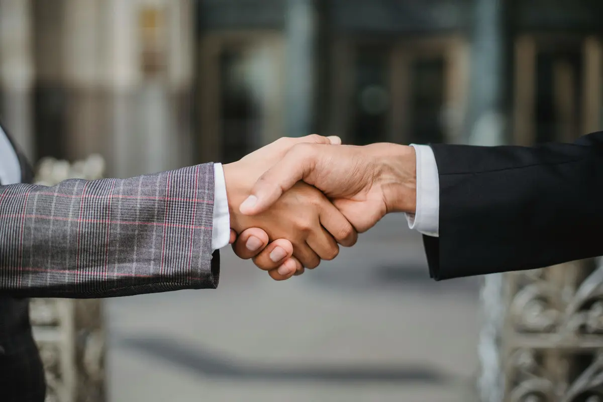 Due persone in abito si stringono la mano